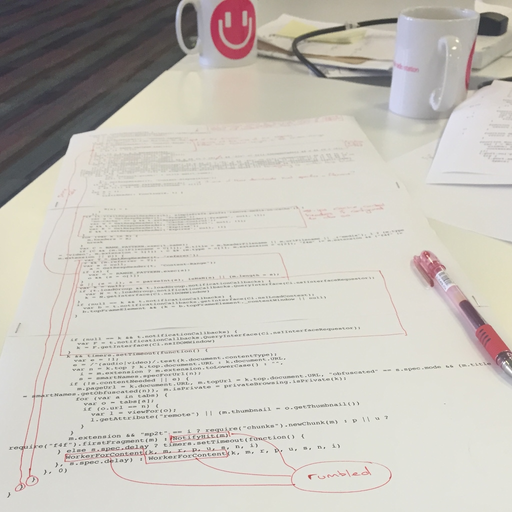 Two printed A4 sheets of paper stapled together with source code on them and red pen markings.